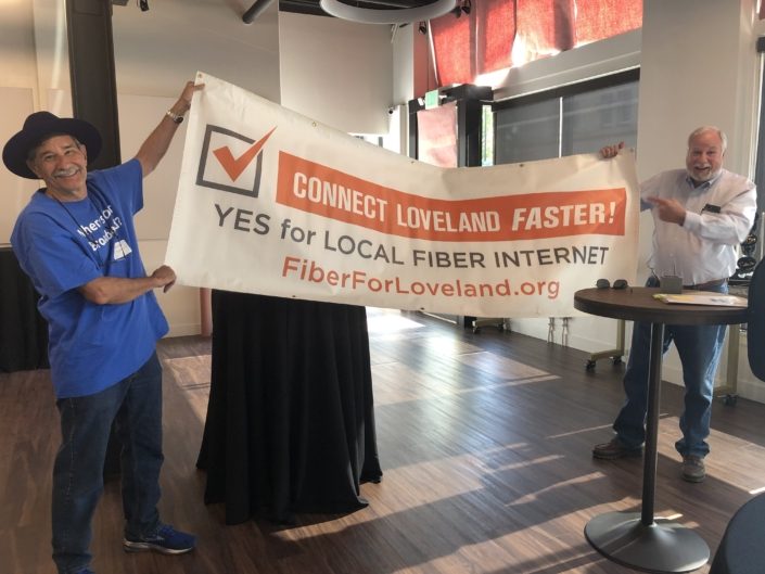Two men holding Fiber for Loveland banner