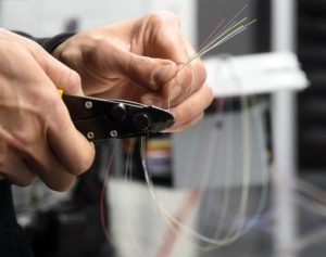 Close up of hands holding a tool working with a line of fiber-optic