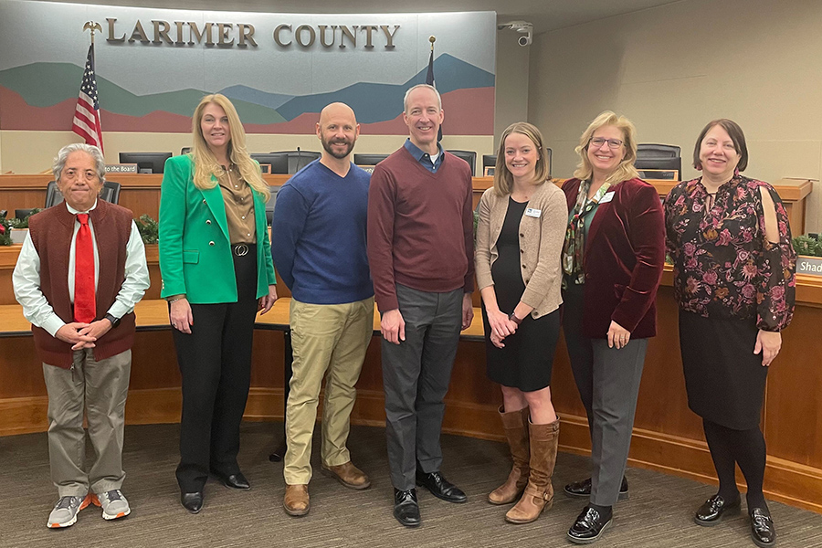A photo of Larimer County and Pulse representatives in front of a Larimer County sign
