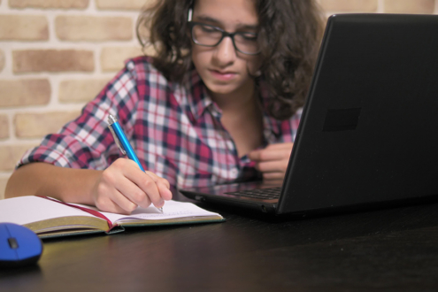Image of student doing homework with a computer and notebook
